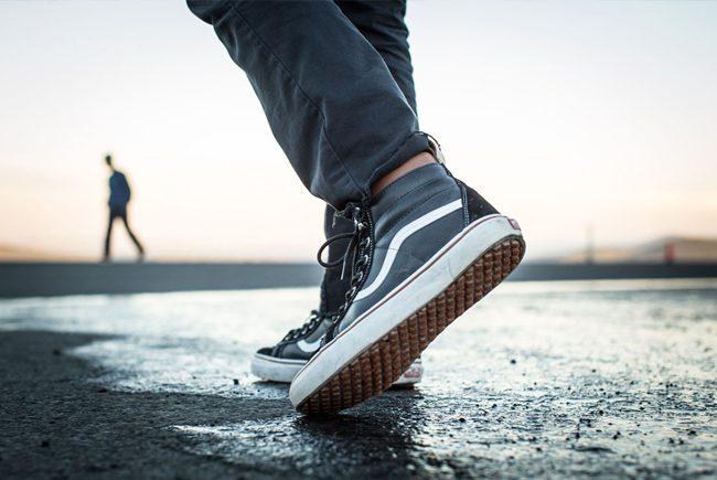 Close-up of a person stepping forward wearing black and white sneakers.