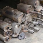 Stacked used car mufflers on floor.