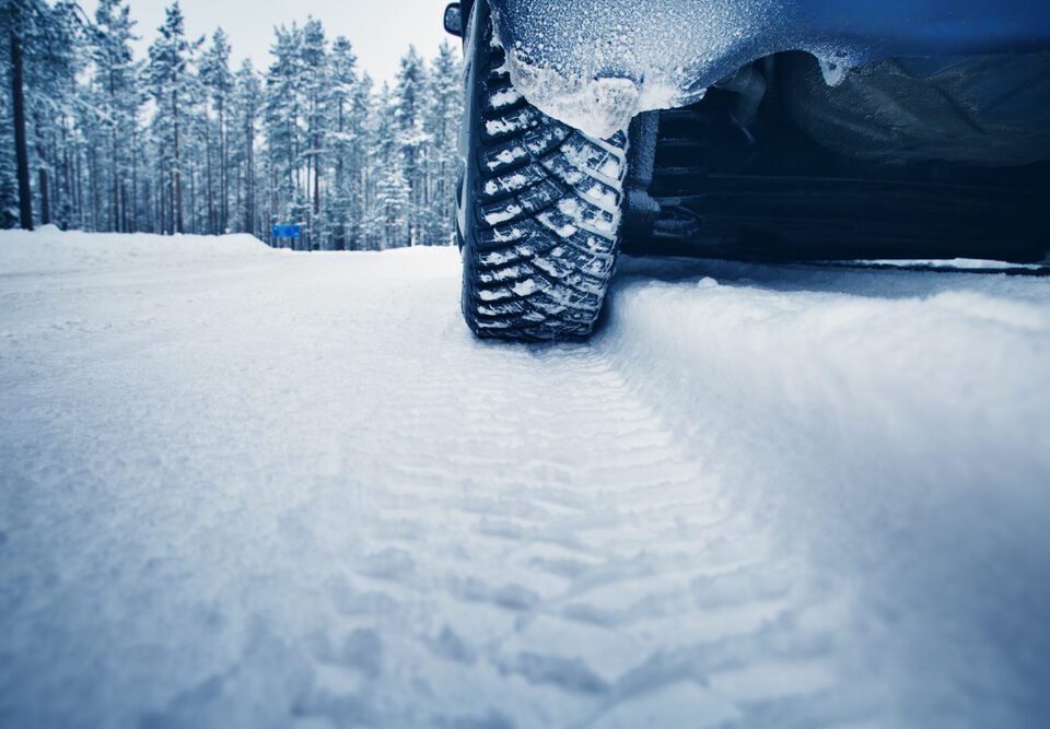 Car tire leaving tracks on snowy road.