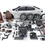 Car with various disassembled auto parts displayed.
