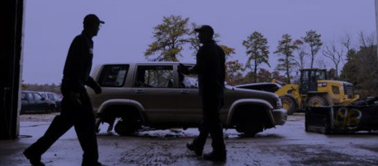 Silhouette of a person standing near a parked truck at dusk.