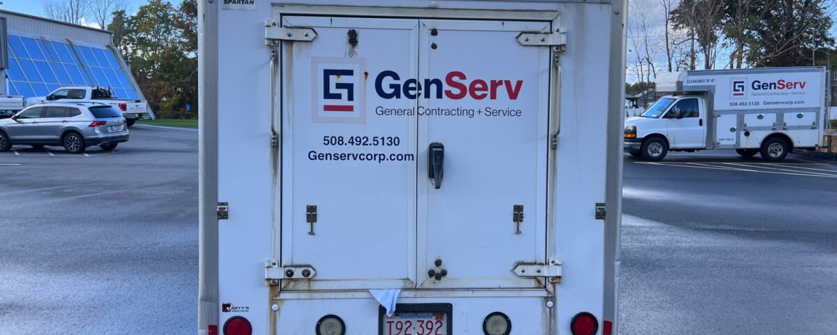 Rear view of a white GenServ utility truck with company branding and contact information.