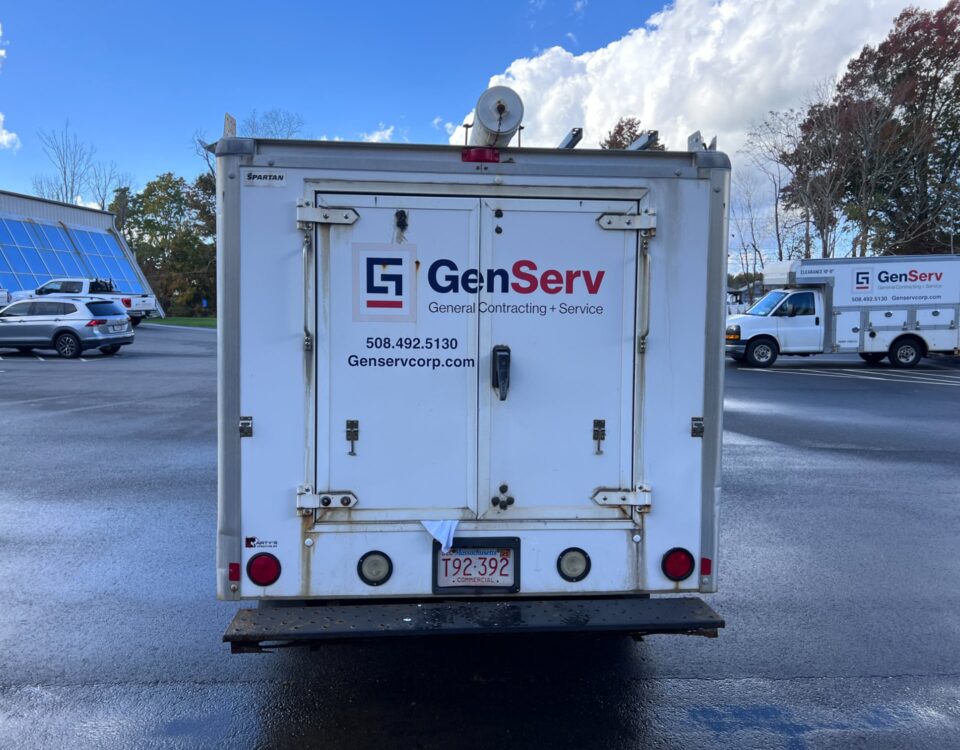 Rear view of a white GenServ utility truck with company branding and contact information.