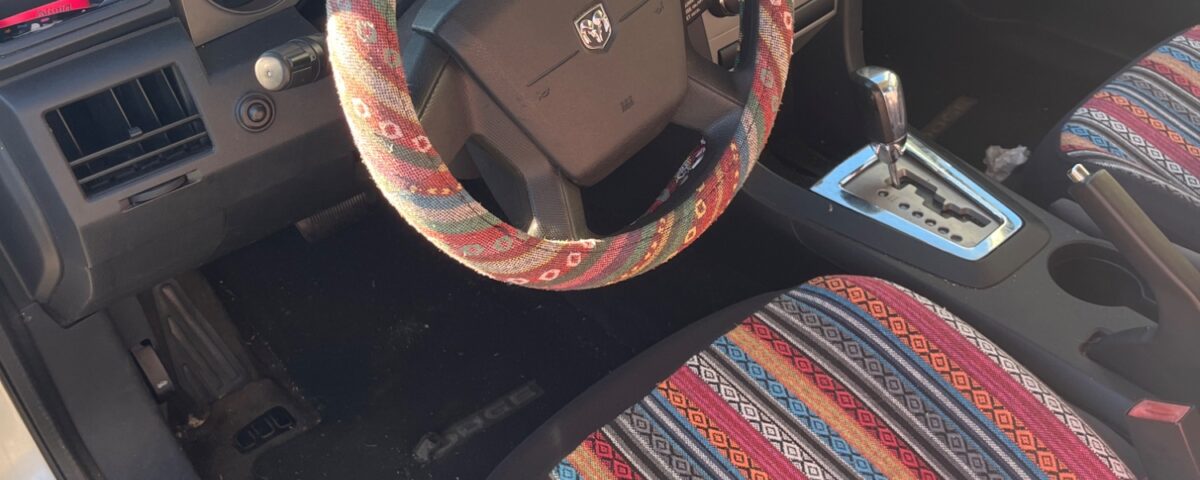 Car interior with colorful striped seat and steering wheel cover.