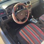 Car interior with colorful striped seat and steering wheel cover.