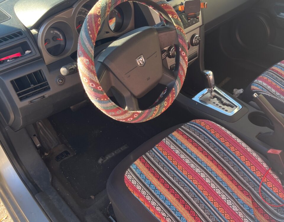 Car interior with colorful striped seat and steering wheel cover.