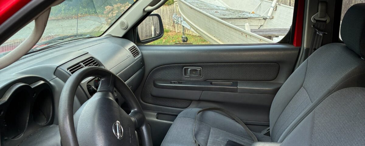 Interior of a red car showing the driver's seat and dashboard.