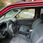 Interior of a red car showing the driver's seat and dashboard.