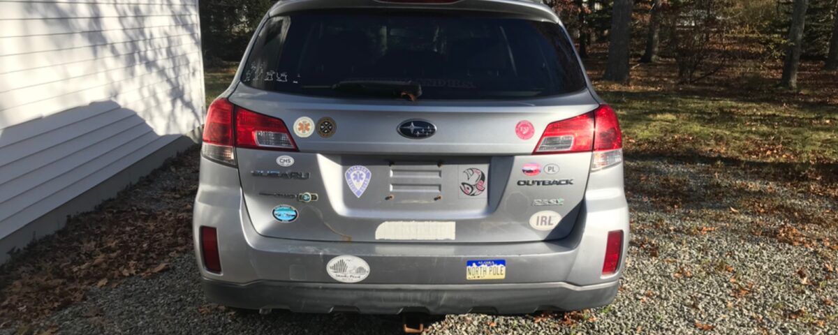 Rear view of a silver Hyundai SUV parked on a gravel driveway.