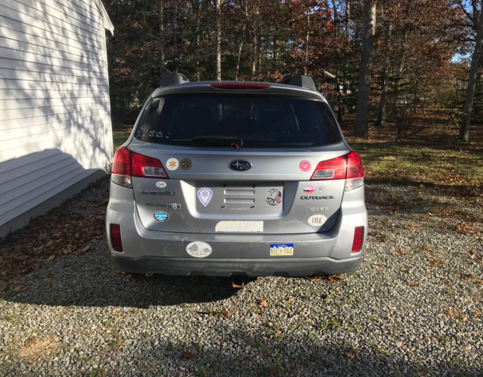 Rear view of a silver Hyundai SUV parked on a gravel driveway.