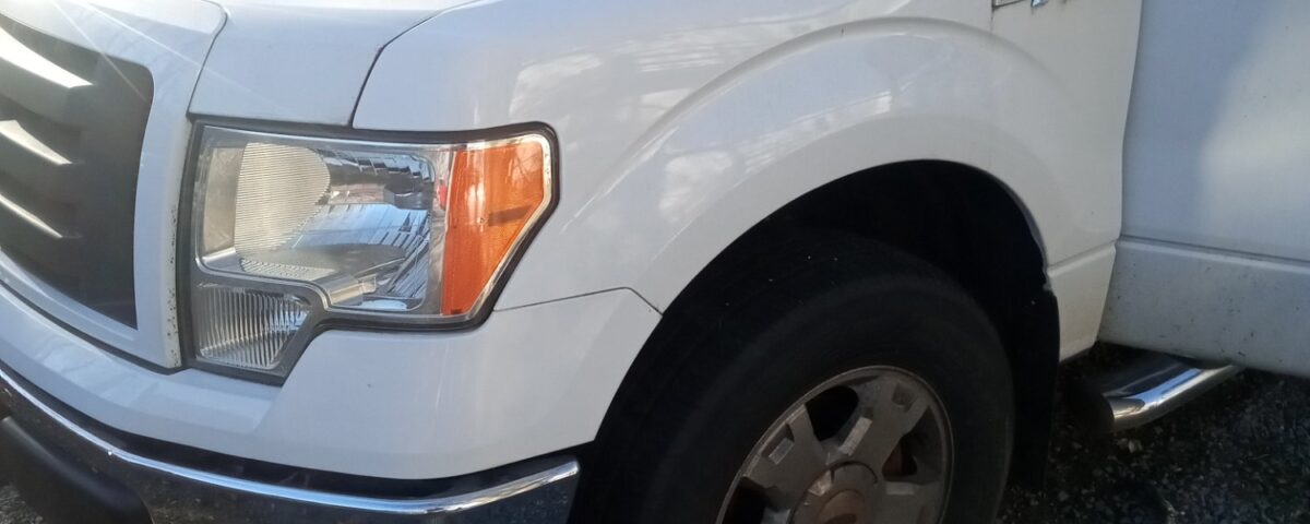 White pickup truck parked on gravel with visible front side.