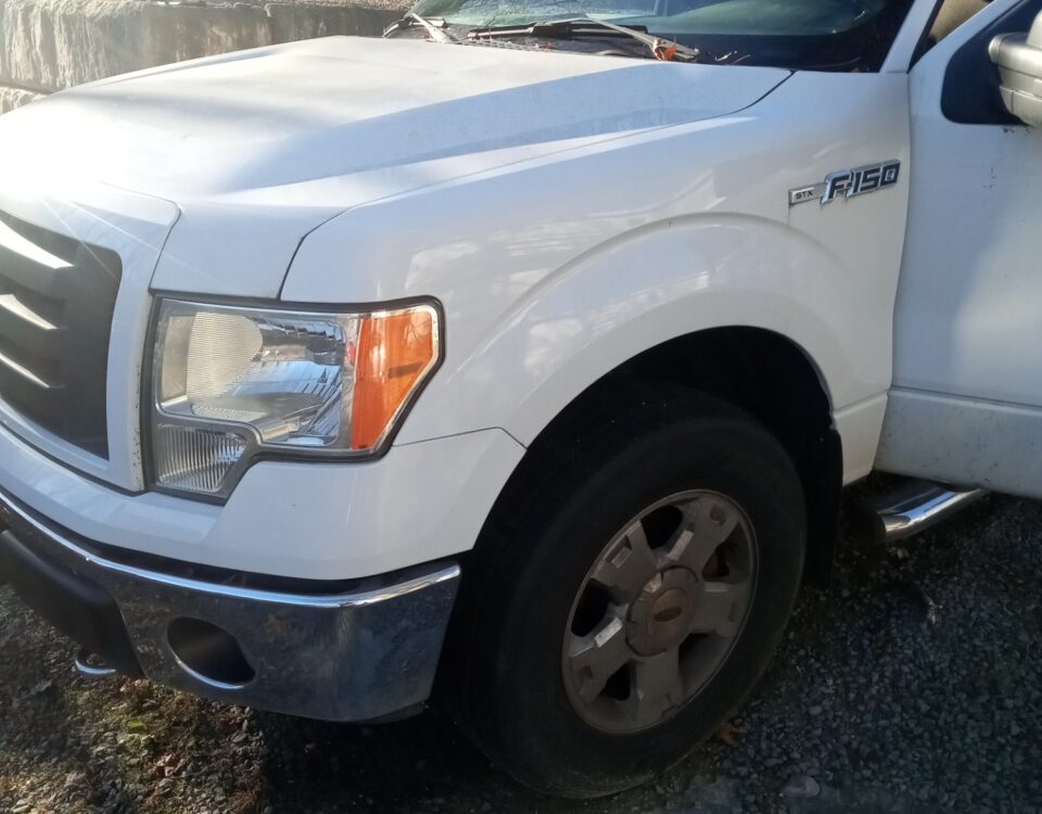 White pickup truck parked on gravel with visible front side.